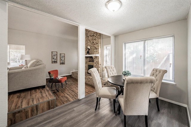 dining area featuring hardwood / wood-style floors, a fireplace, and a textured ceiling