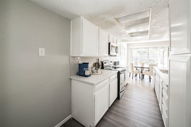 kitchen featuring white cabinetry, stainless steel appliances, hardwood / wood-style floors, a textured ceiling, and decorative backsplash