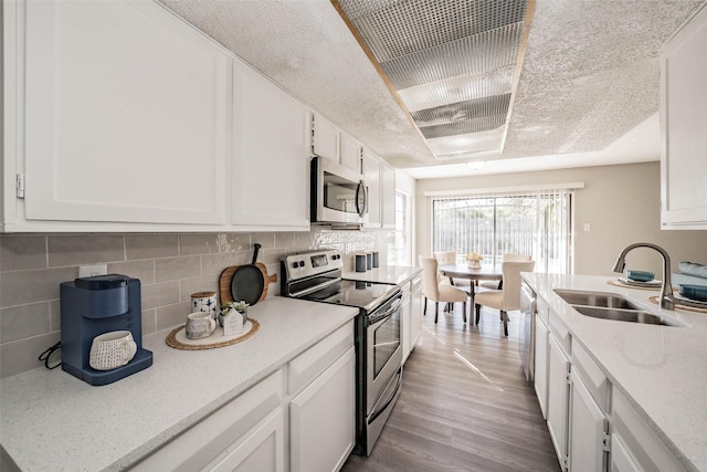 kitchen with white cabinets, appliances with stainless steel finishes, tasteful backsplash, and sink