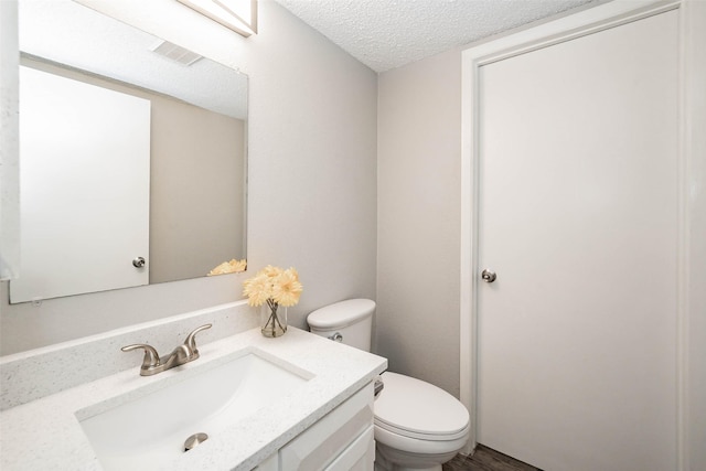 bathroom with vanity, hardwood / wood-style floors, a textured ceiling, and toilet