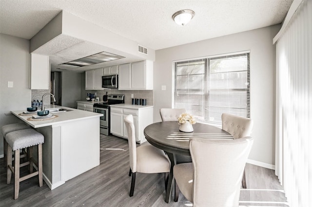 dining space featuring a textured ceiling, light hardwood / wood-style floors, and sink