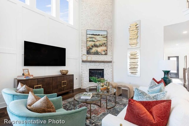 living room with hardwood / wood-style flooring, a towering ceiling, and a fireplace