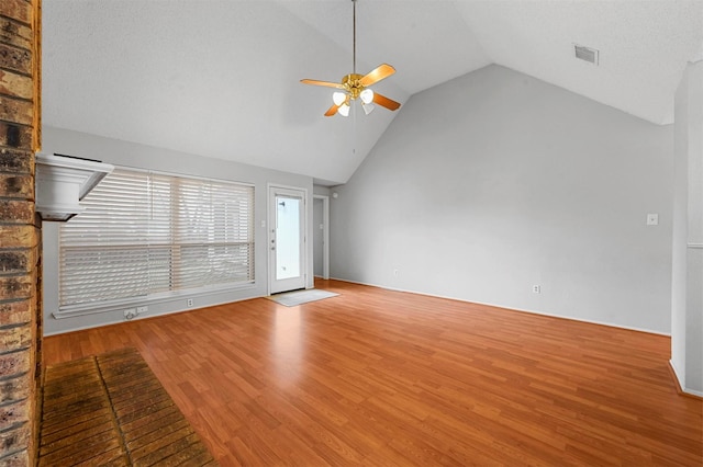 unfurnished living room with ceiling fan, vaulted ceiling, a textured ceiling, and light hardwood / wood-style flooring