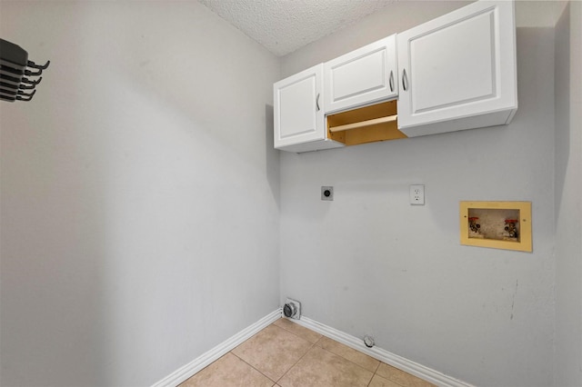 laundry room with cabinets, electric dryer hookup, hookup for a washing machine, a textured ceiling, and light tile patterned floors