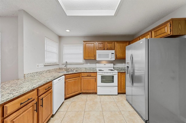 kitchen with a textured ceiling, sink, light tile patterned floors, and white appliances