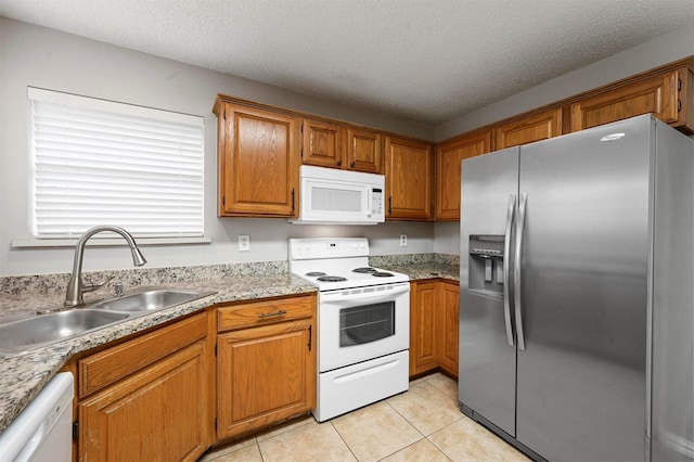 kitchen featuring light tile patterned flooring, a textured ceiling, white appliances, and sink