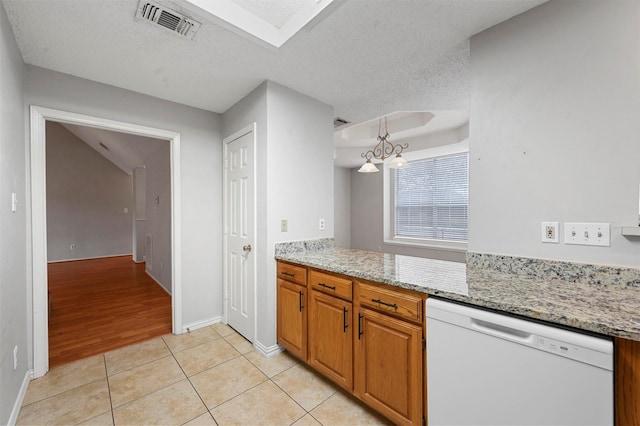 kitchen featuring a textured ceiling, white dishwasher, light tile patterned floors, and a notable chandelier