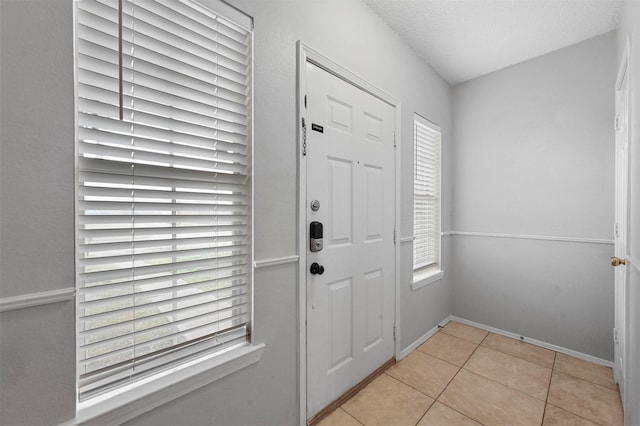 foyer with light tile patterned floors, a textured ceiling, and a healthy amount of sunlight