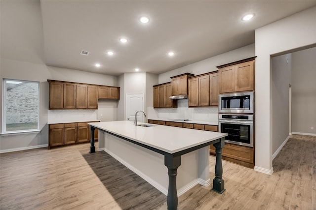 kitchen featuring a breakfast bar, black electric cooktop, built in microwave, sink, and oven