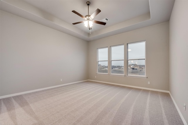 carpeted spare room featuring a tray ceiling and ceiling fan