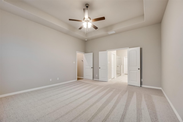 carpeted spare room with a high ceiling, a tray ceiling, and ceiling fan