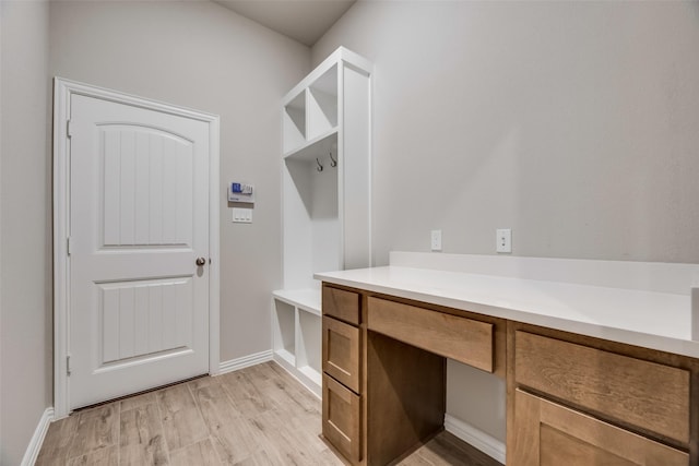 mudroom with built in desk and light hardwood / wood-style floors