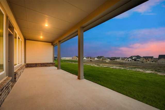 patio terrace at dusk featuring a yard