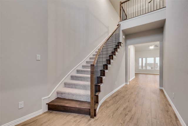 stairs with hardwood / wood-style flooring, ceiling fan, and a towering ceiling