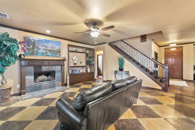 living room with ceiling fan, a fireplace, and ornamental molding