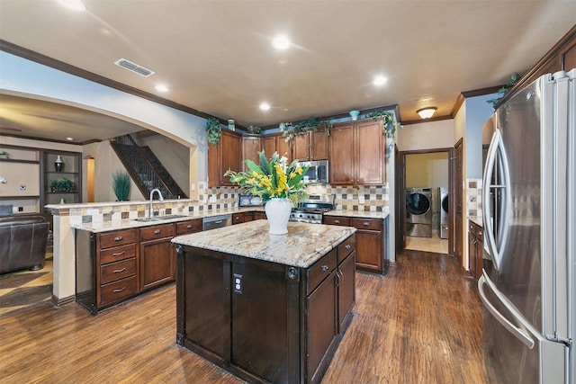 kitchen with a center island, backsplash, sink, stainless steel appliances, and washing machine and clothes dryer