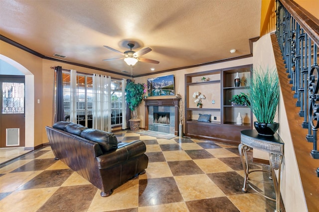 living room featuring ceiling fan, crown molding, and a textured ceiling