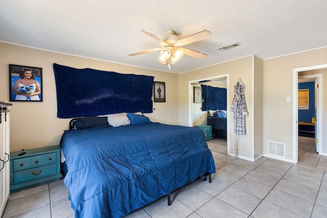 bedroom with ceiling fan, light tile patterned flooring, and a textured ceiling