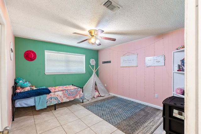 bedroom with ceiling fan, light tile patterned floors, and a textured ceiling