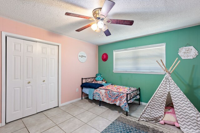 bedroom featuring light tile patterned floors, a textured ceiling, a closet, and ceiling fan