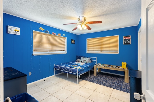 bedroom with ceiling fan, tile patterned flooring, and a textured ceiling