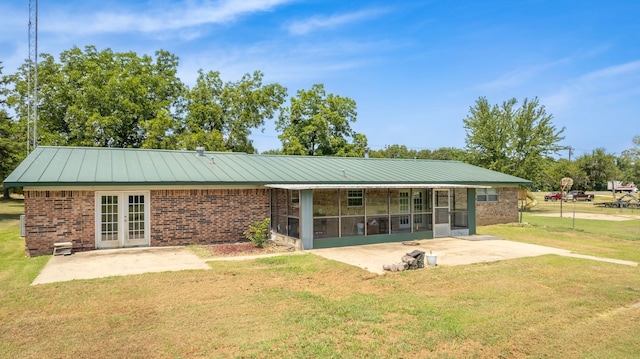 rear view of house featuring a yard, a patio, french doors, and a sunroom