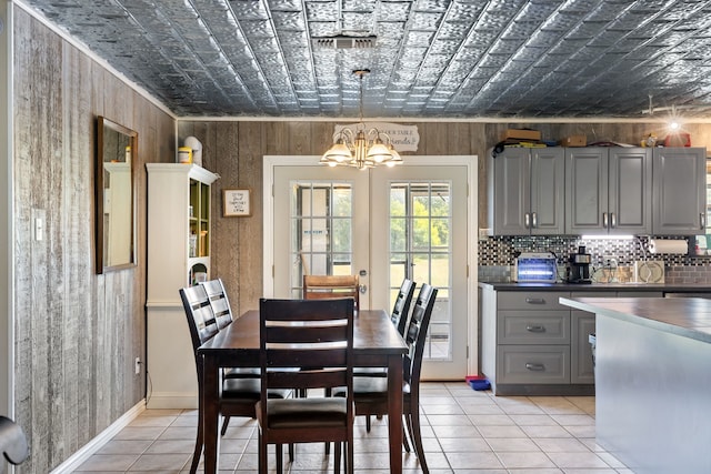 tiled dining space featuring a chandelier and french doors