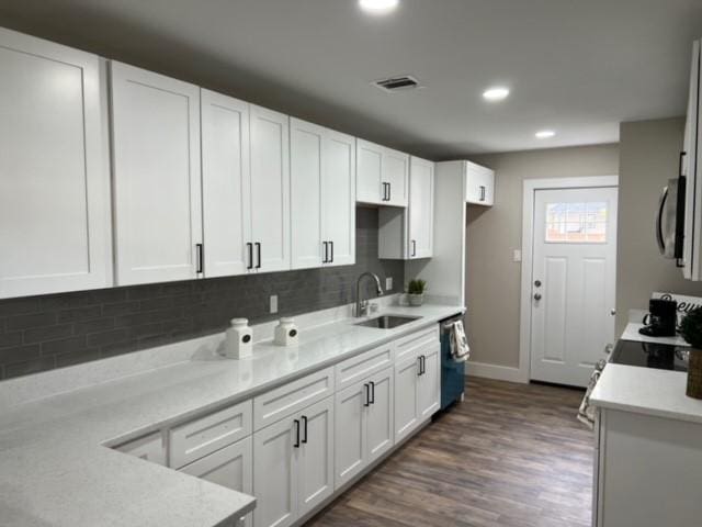 kitchen featuring sink, dark hardwood / wood-style floors, backsplash, dishwashing machine, and white cabinets