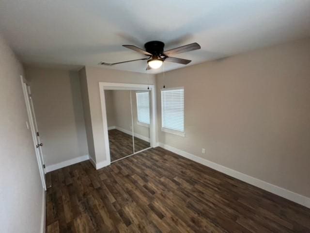 unfurnished bedroom featuring ceiling fan, dark wood-type flooring, and a closet