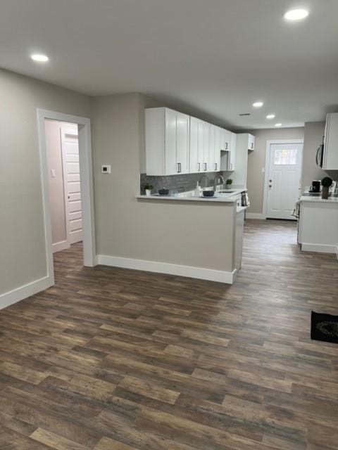 kitchen with kitchen peninsula, decorative backsplash, dark hardwood / wood-style flooring, and white cabinets