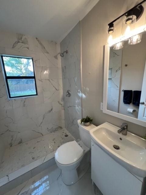 bathroom with tiled shower, vanity, and toilet