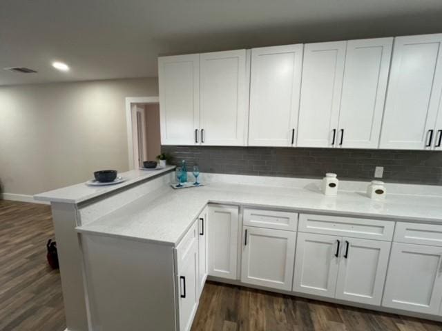 232 Alto Dr, Garland, TX 75040 - kitchen with a peninsula, white cabinets, light countertops, backsplash, and dark wood finished floors