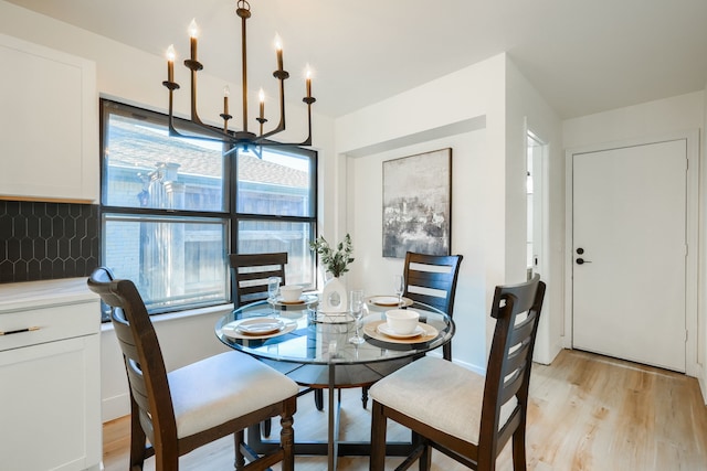 dining area with light hardwood / wood-style floors and an inviting chandelier