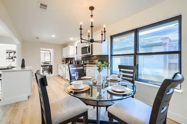 dining space featuring light hardwood / wood-style floors, sink, and an inviting chandelier