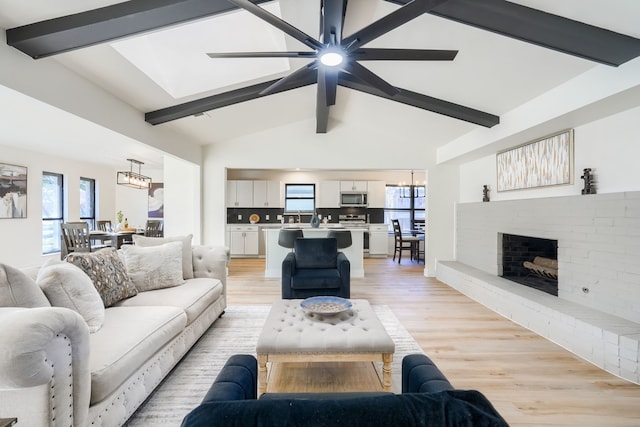 living room with vaulted ceiling with beams, a healthy amount of sunlight, a fireplace, and ceiling fan