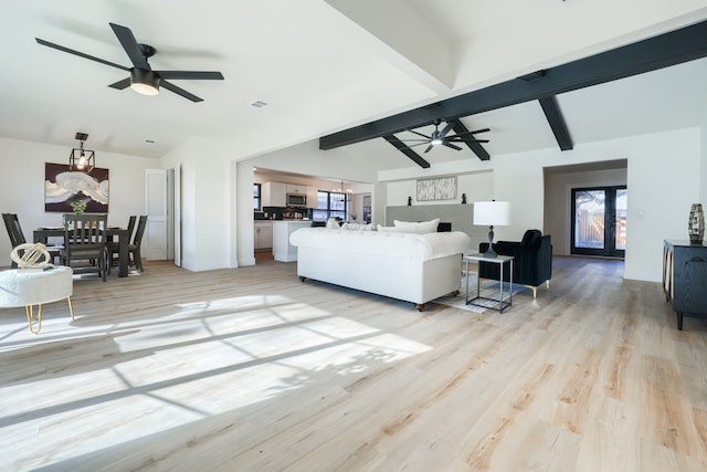 living room with lofted ceiling with beams, ceiling fan, french doors, and light hardwood / wood-style flooring