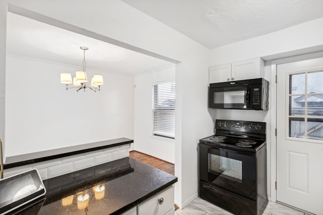 kitchen with a textured ceiling, black appliances, pendant lighting, an inviting chandelier, and white cabinets