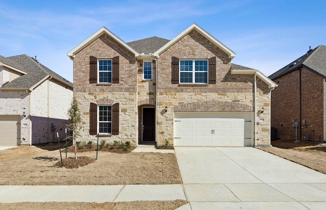 traditional-style house with a shingled roof, concrete driveway, stone siding, an attached garage, and brick siding