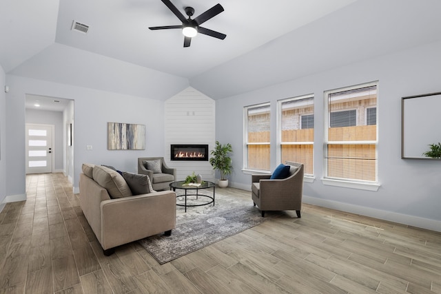 living room with ceiling fan, lofted ceiling, and a fireplace