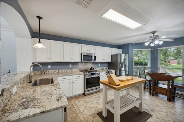 kitchen featuring light stone countertops, stainless steel appliances, sink, decorative light fixtures, and white cabinets