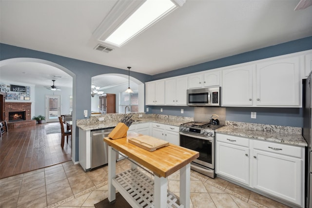 kitchen with white cabinets, decorative light fixtures, ceiling fan, and appliances with stainless steel finishes