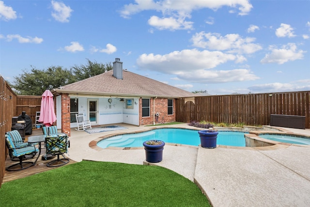 view of swimming pool featuring a lawn, a patio area, and an in ground hot tub