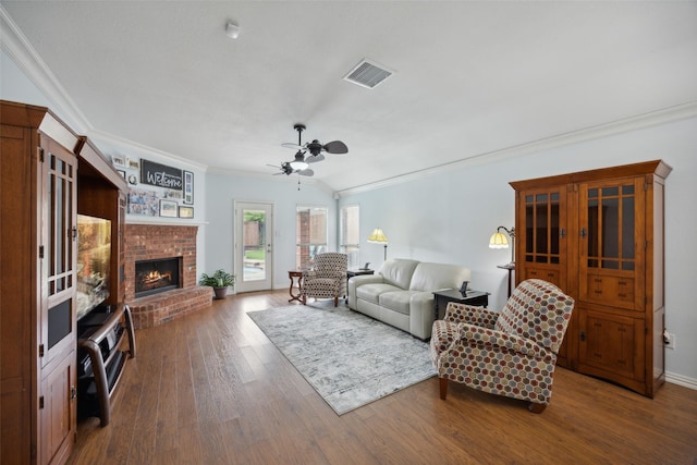 living room featuring a brick fireplace, ceiling fan, hardwood / wood-style flooring, and ornamental molding