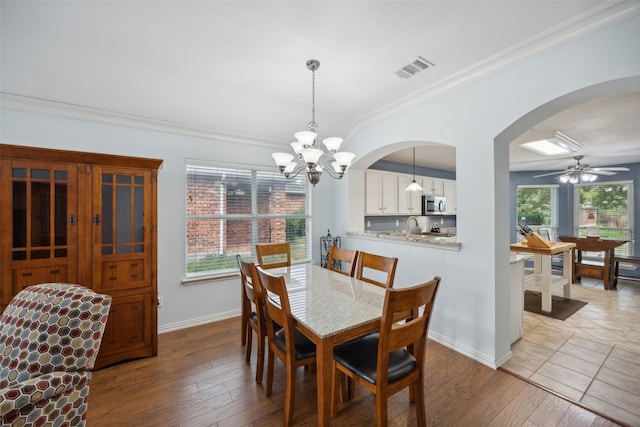 dining room with light wood-type flooring, ceiling fan with notable chandelier, ornamental molding, and sink