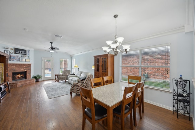 dining area with a fireplace, ceiling fan with notable chandelier, dark wood-type flooring, and ornamental molding