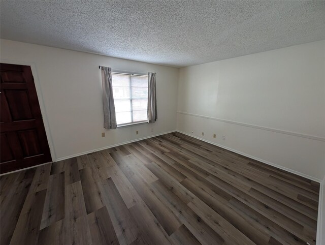 spare room with a textured ceiling and dark wood-type flooring