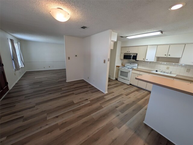 kitchen featuring electric range, sink, dark hardwood / wood-style flooring, backsplash, and white cabinets