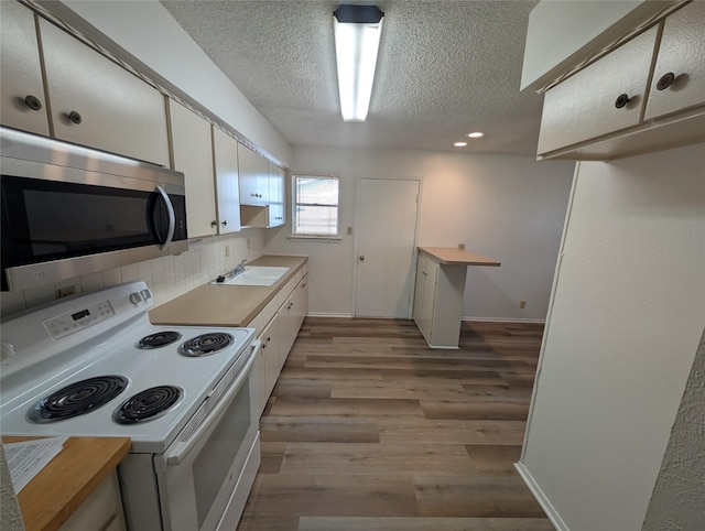 kitchen featuring white cabinetry, electric range, sink, tasteful backsplash, and light wood-type flooring