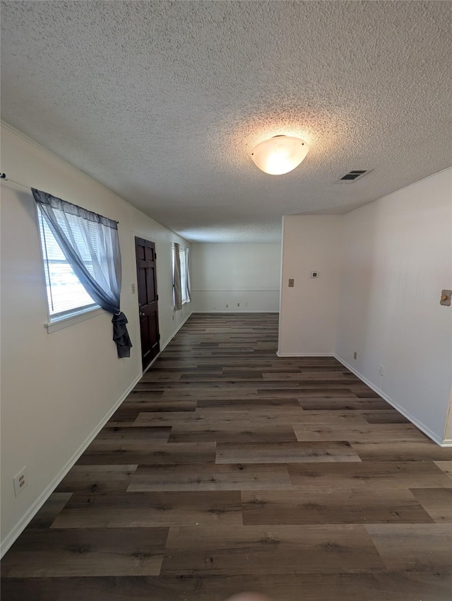 corridor with a textured ceiling and dark hardwood / wood-style floors