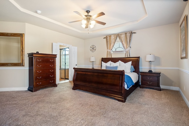 carpeted bedroom featuring a raised ceiling and ceiling fan